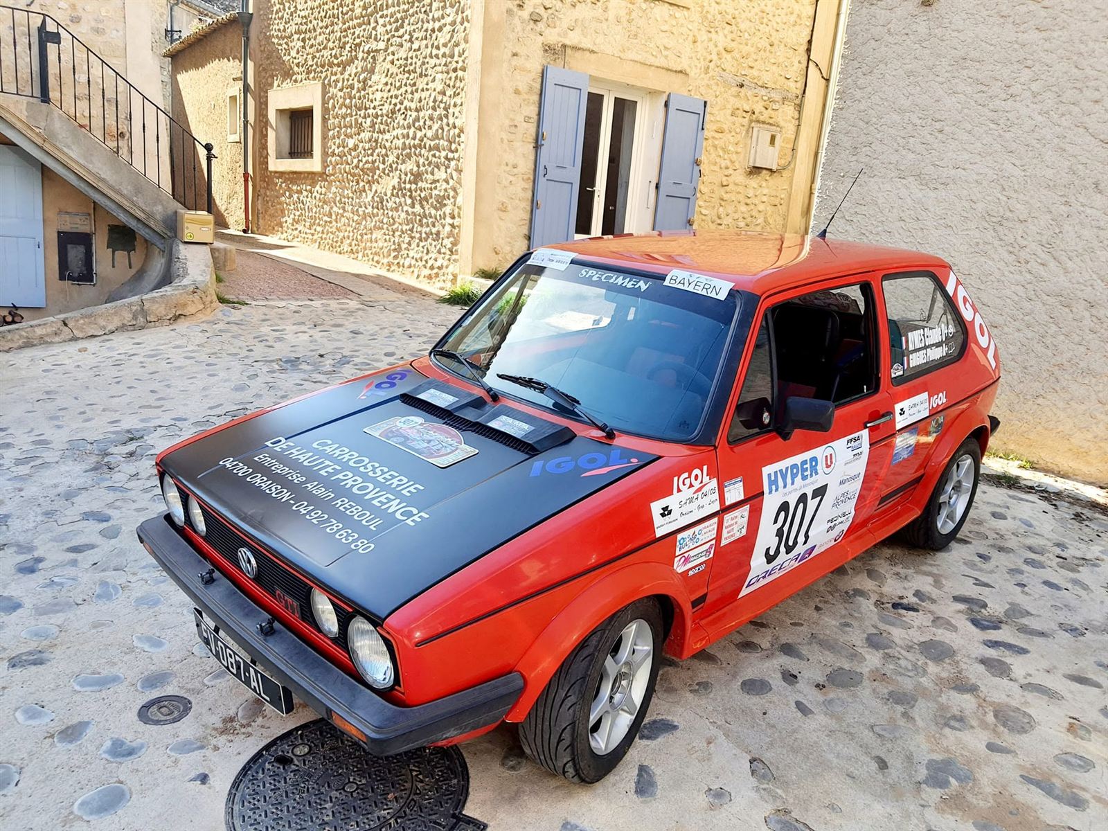 Voiture de rallye rouge vue de trois quarts, portières ouvertes