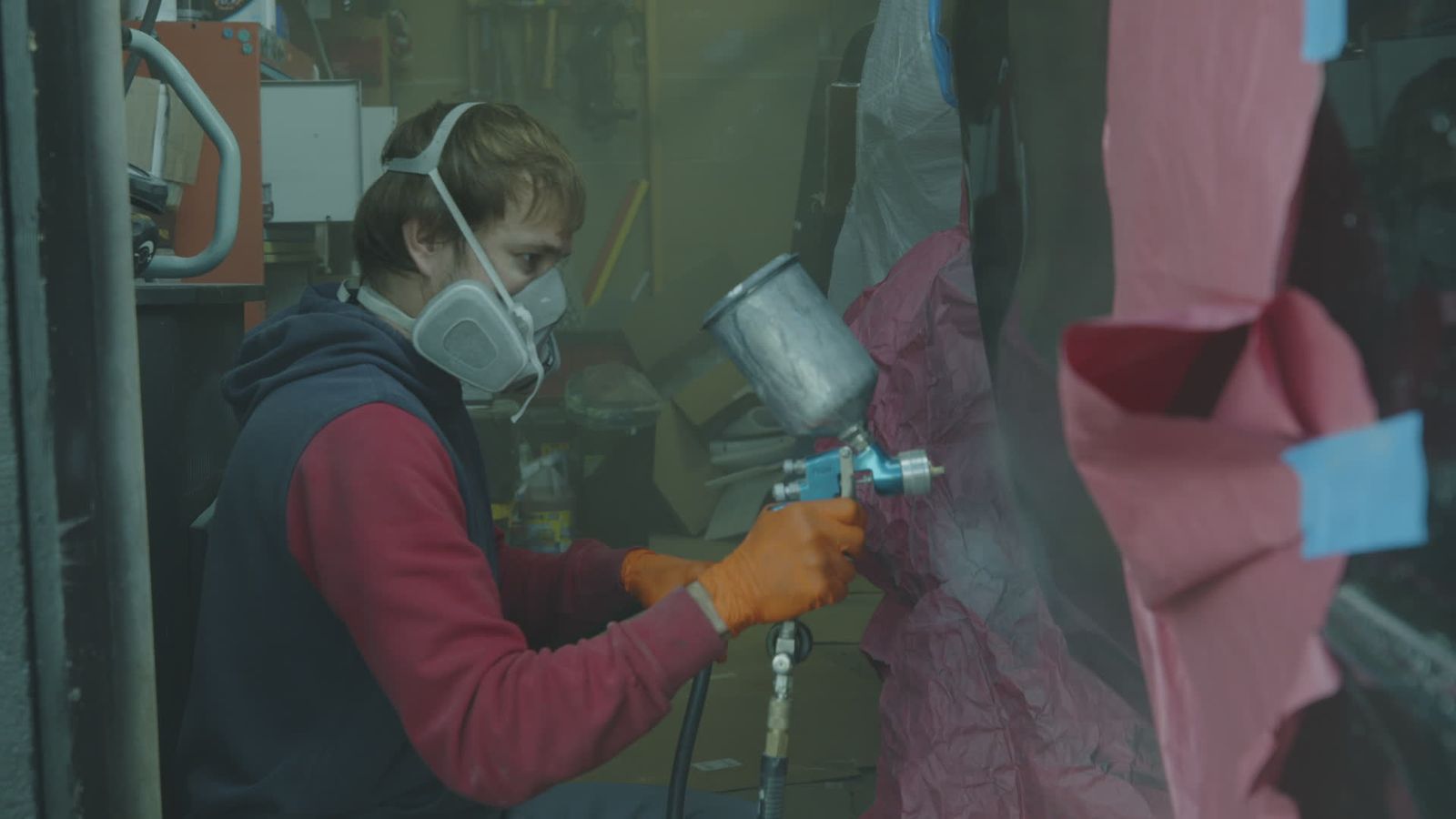 Peintre en combinaison et masque au pistolet dans l’atelier de peinture